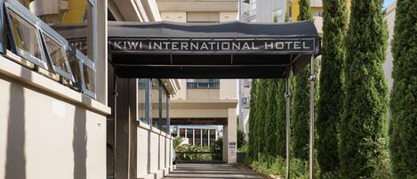Ein Weg zum KIWI INTERNATIONAL HOTEL mit überdachter Eingangspartei und einem Schild darüber.