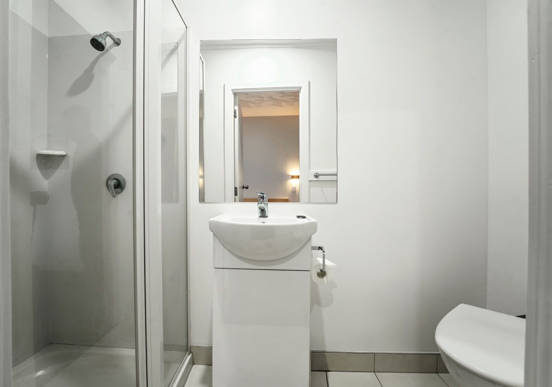 A bathroom with a shower, sink, mirror, and toilet.