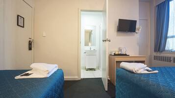 A hotel room with two beds, a desk, a television, and a bathroom visible through an open door.