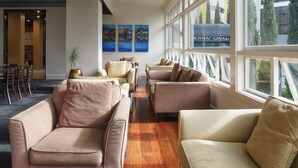 A spacious lobby with a modern design, featuring a long reception desk, comfortable seating areas, and large windows offering views of the cityscape. - Kiwi International Hotel (Auckland)