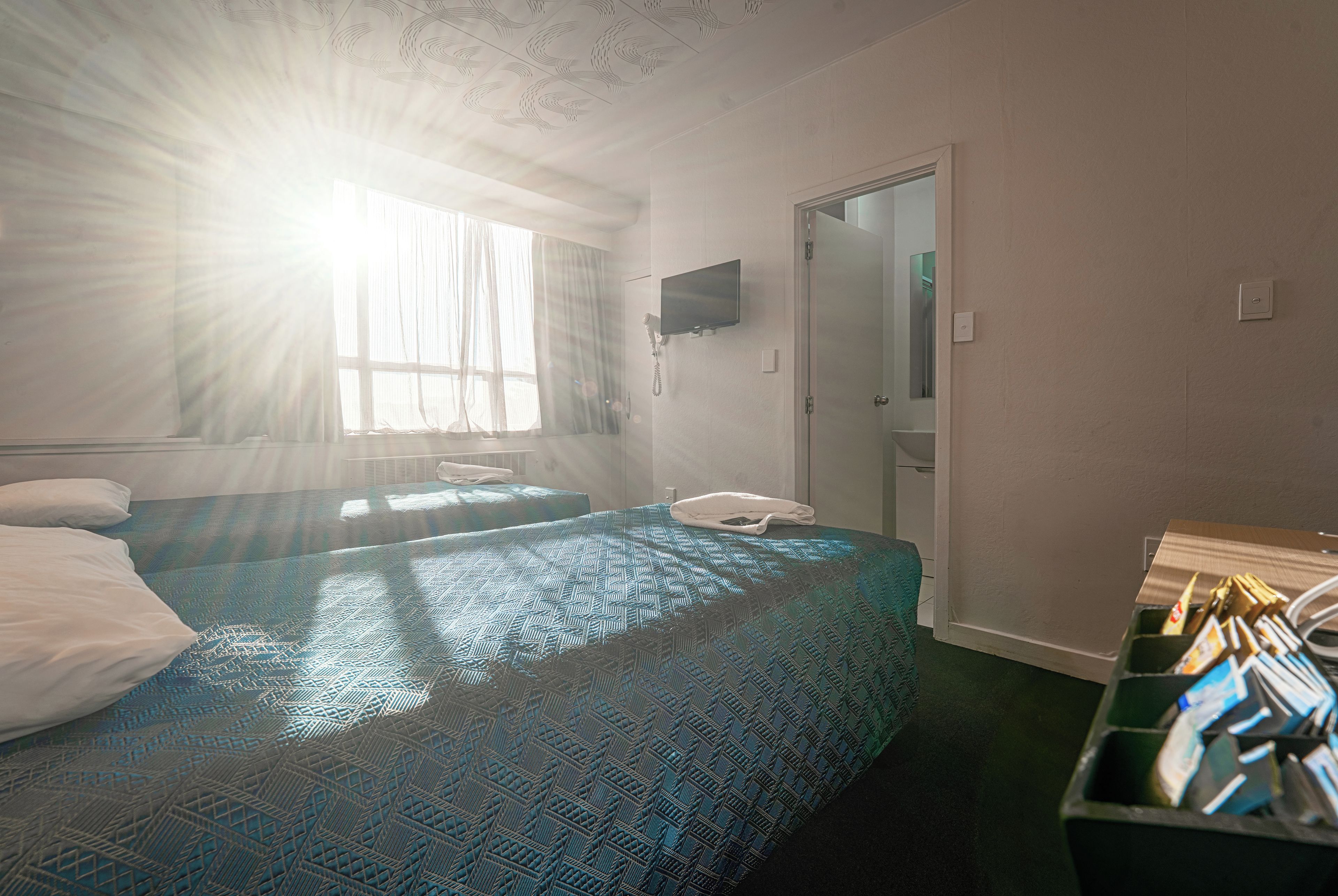 A hotel room with two beds, a television, a telephone, and a minibar.