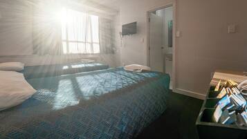 A hotel room with two beds, a television, a telephone, and a minibar.