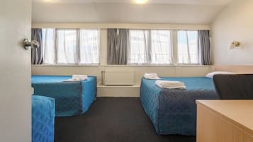 A room with two beds, a radiator, and a desk.