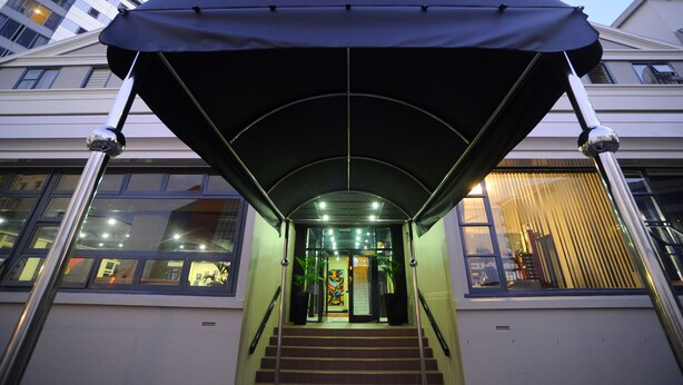 A hotel entrance with a covered staircase and a large umbrella. - Kiwi International Hotel (Auckland)