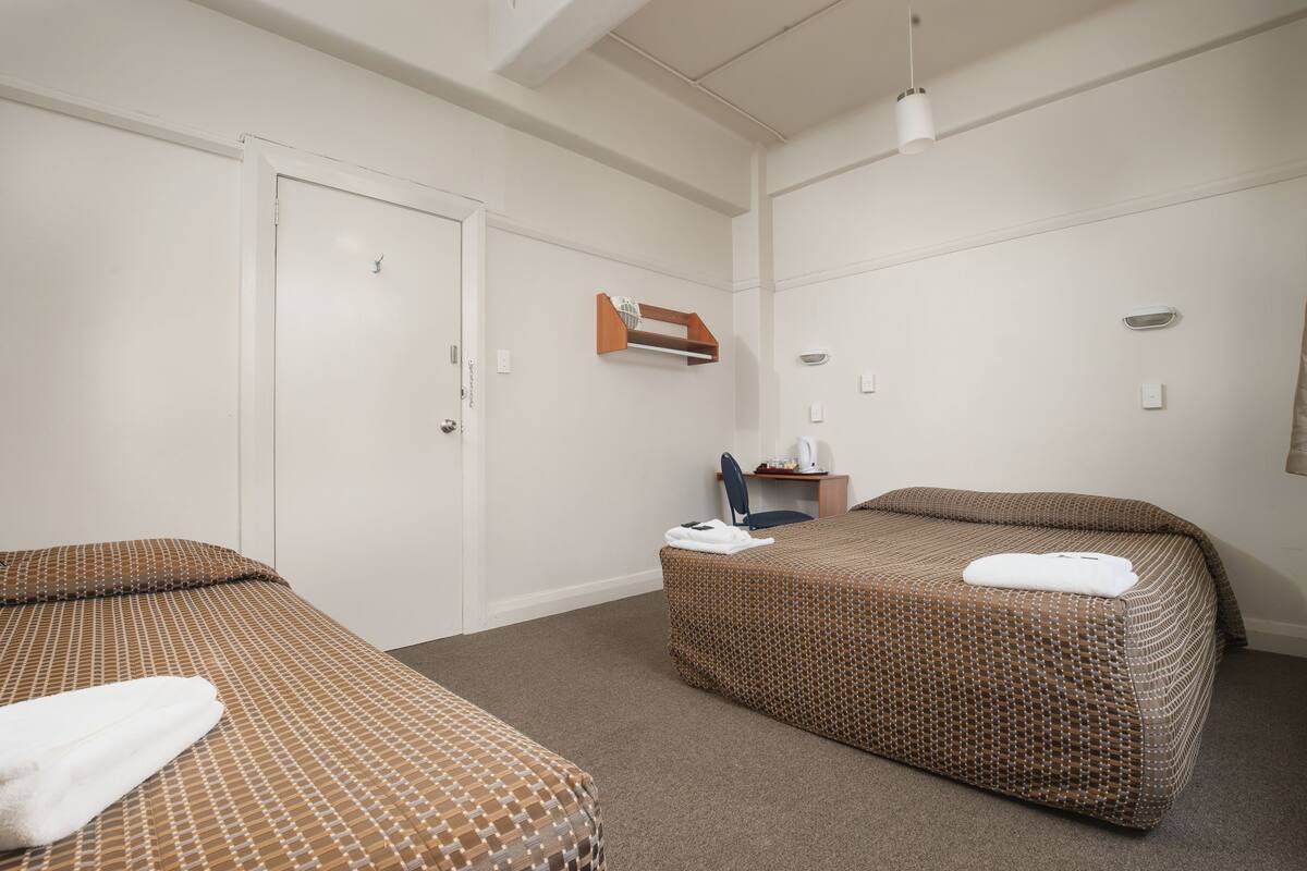 A hotel room with two beds, a desk, and a chair.