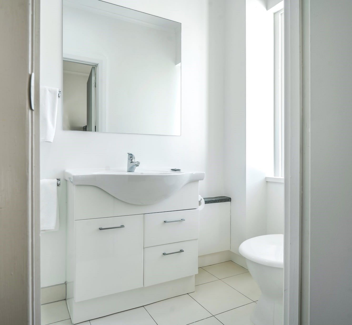A bathroom with a white sink, a mirror, and a toilet.