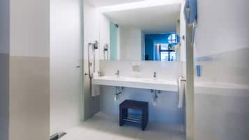 Un baño moderno con un espejo grande, lavamanos blanco y un taburete pequeño.