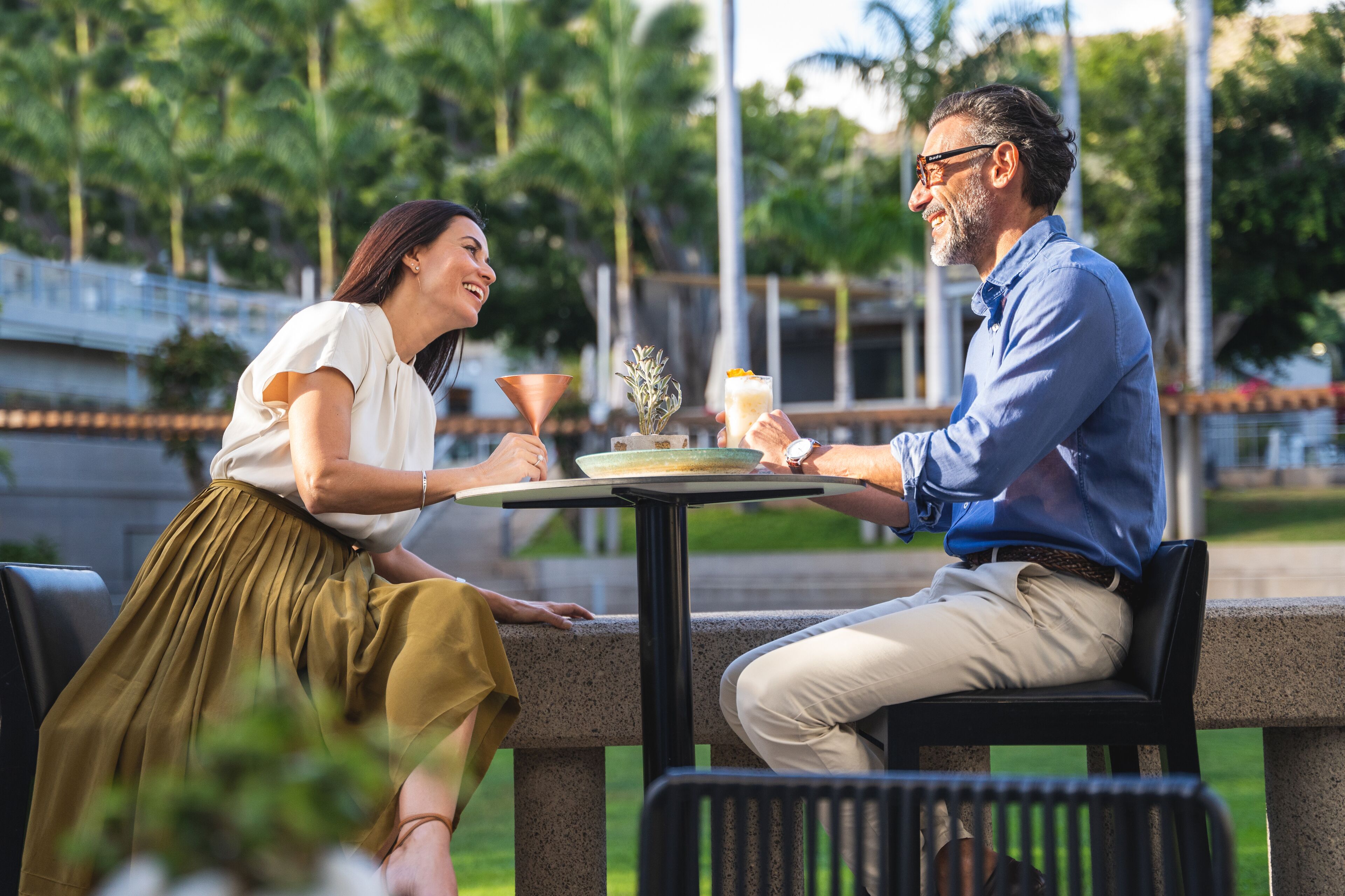 Two people seated at an outdoor table with a drink and a decorative item.