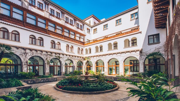 A courtyard with a fountain, surrounded by arched windows and a white building with wooden balconies. - Iberostar Heritage Grand Mencey (Santa Cruz de Tenerife)