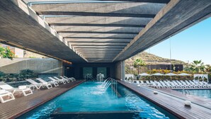 A swimming pool with a wooden deck, lounge chairs, and a concrete ceiling structure. - Iberostar Heritage Grand Mencey (Santa Cruz de Tenerife)