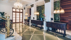 A lobby with a grand chandelier, a reception desk, and a check-in counter. - Iberostar Heritage Grand Mencey (Santa Cruz de Tenerife)
