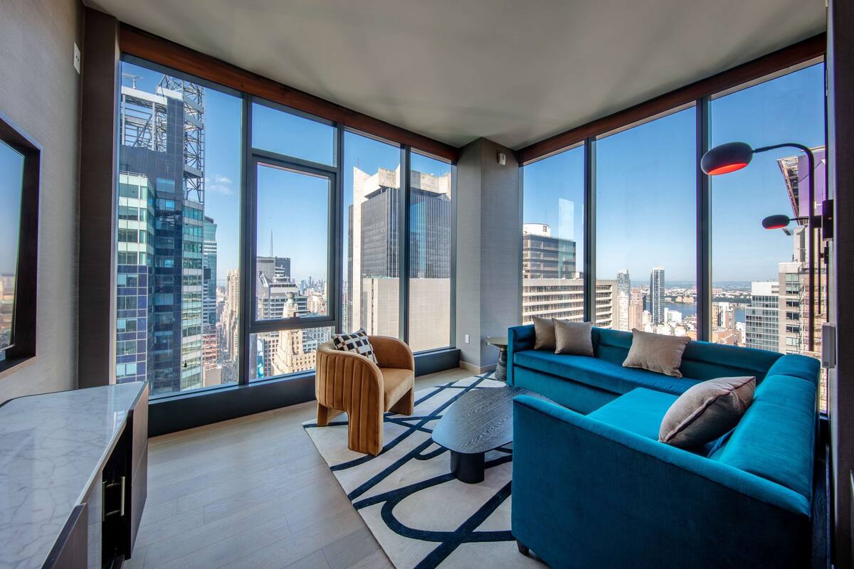 A modern living room with large windows, a sofa, a coffee table, and a small table.