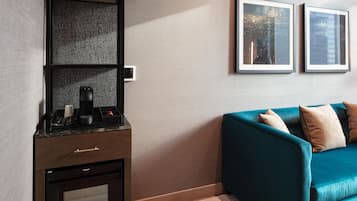 Uma sala de estar moderna com um sofá verde-turquesa, uma máquina de café e um quadro pendurado na parede.