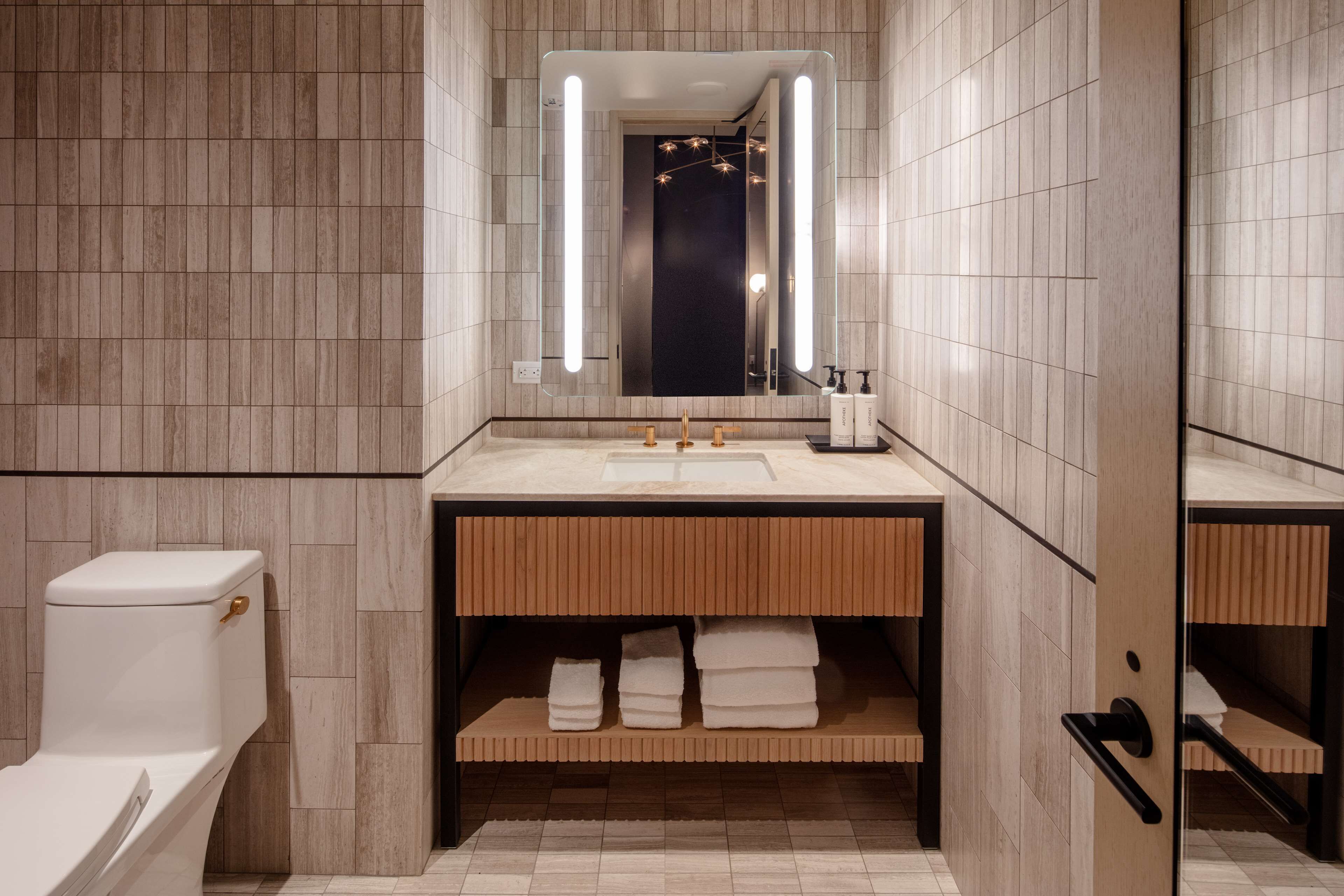 A modern bathroom with a wooden vanity, a large mirror, and a toilet.