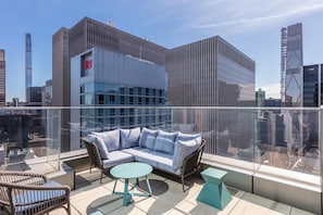 A rooftop terrace with a sofa set, a round table, and a chair. - Tempo by Hilton New York Times Square (New York)