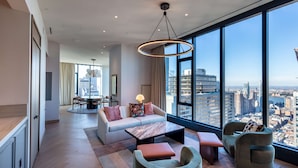 A modern living room with a large window, a sofa, a coffee table, and a dining area. - Tempo by Hilton New York Times Square (New York)