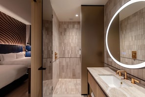 Une salle de bain moderne avec un grand miroir, un lavabo et un espace douche.
