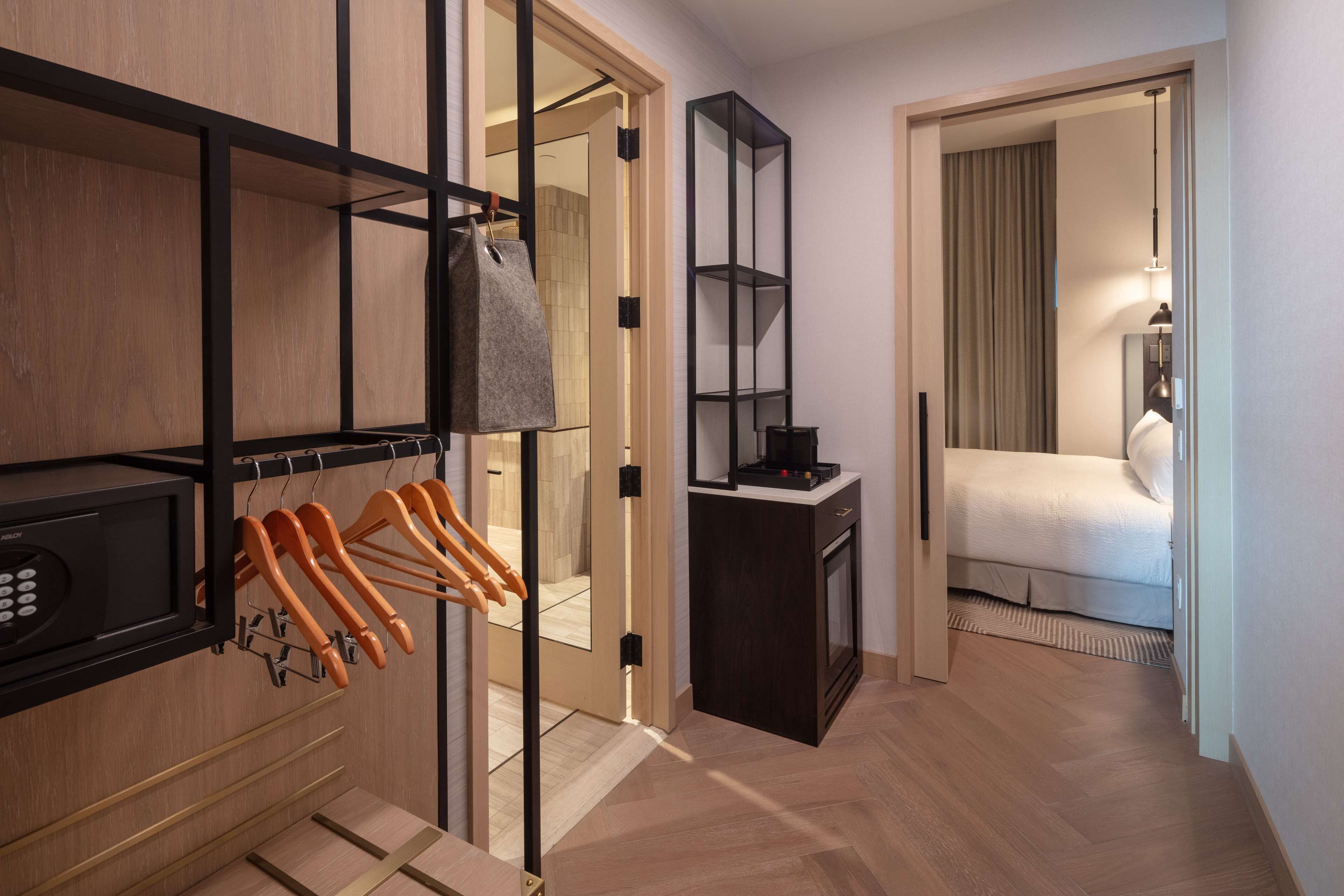 Een hotelkamer met een houten kast, een klein bureau, een bed en een spiegel.