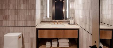 A modern bathroom with a toilet, sink, mirror, and towel rack.