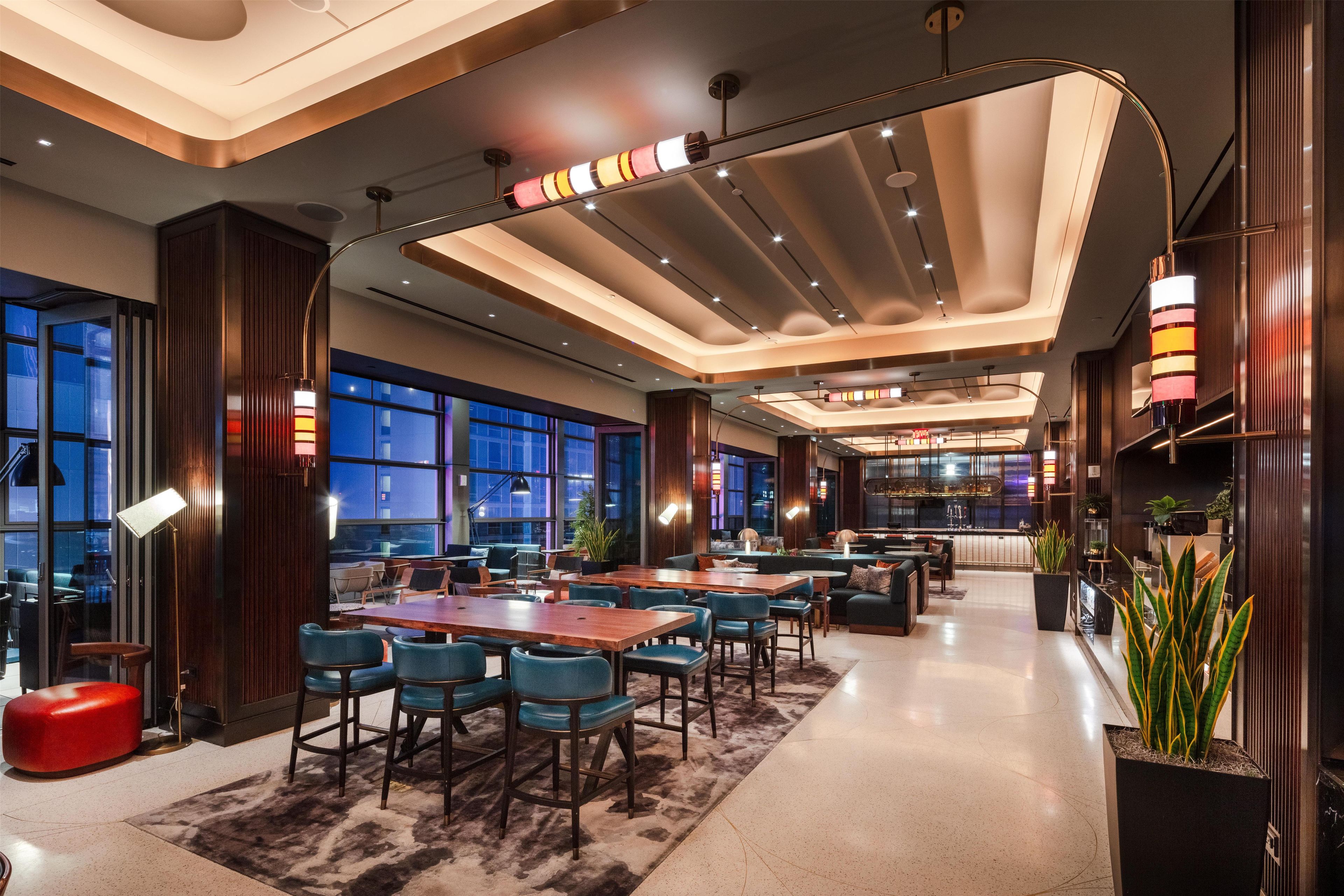 A modern hotel lobby with a bar area, seating arrangements, and large windows.