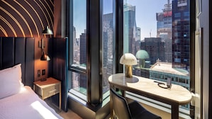 Een moderne hotelkamer met een groot raam, een bed, een bureau en een lamp.