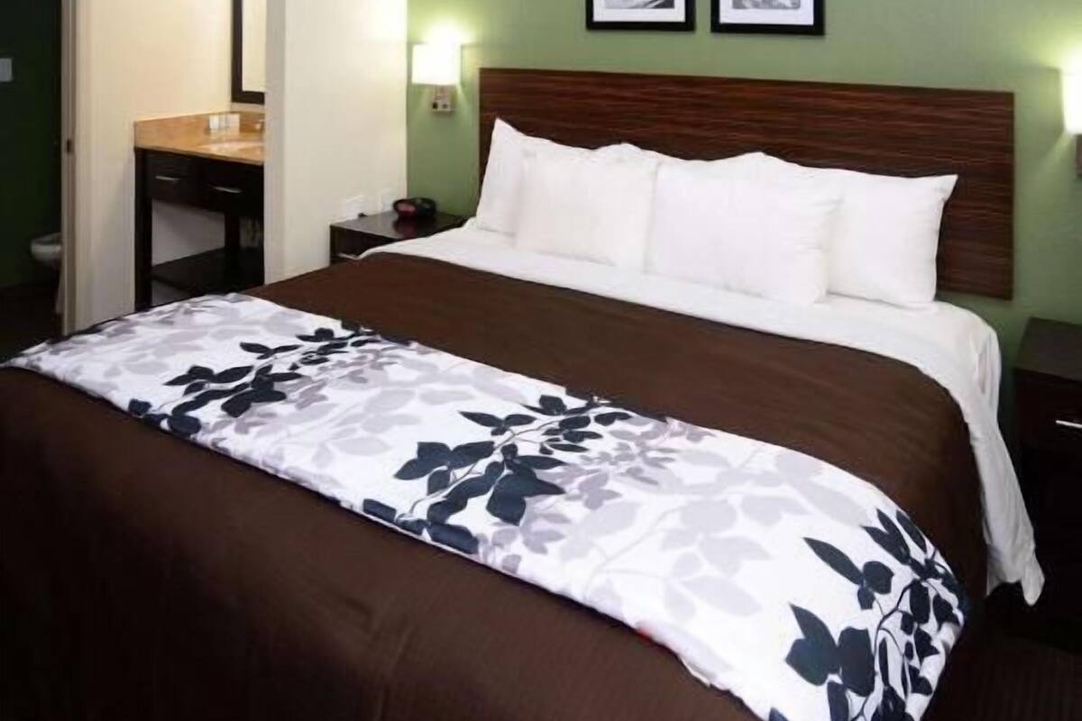 Ein Hotelzimmer mit einem Bett, einem Nachttisch, Spiegel und gerahmten Bildern an der Wand.