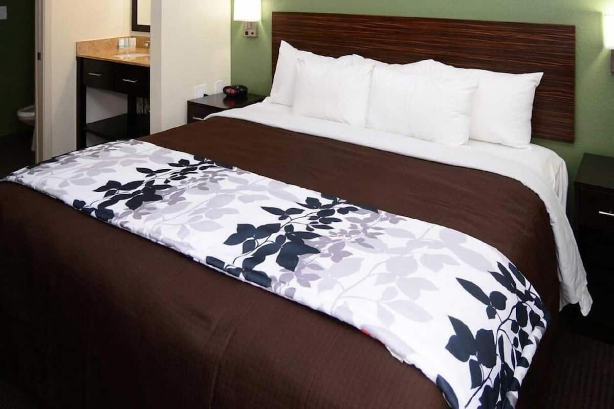 Ein Hotelzimmer mit Bett, Nachttisch, Schreibtisch und einem Wandbild.