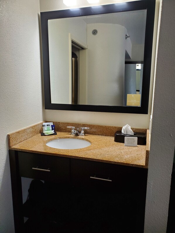 A bathroom with a sink, two faucets, a mirror, and a tissue box.