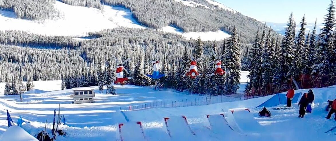 A ski resort with snow-covered slopes, a small lodge, and a forested mountain backdrop.