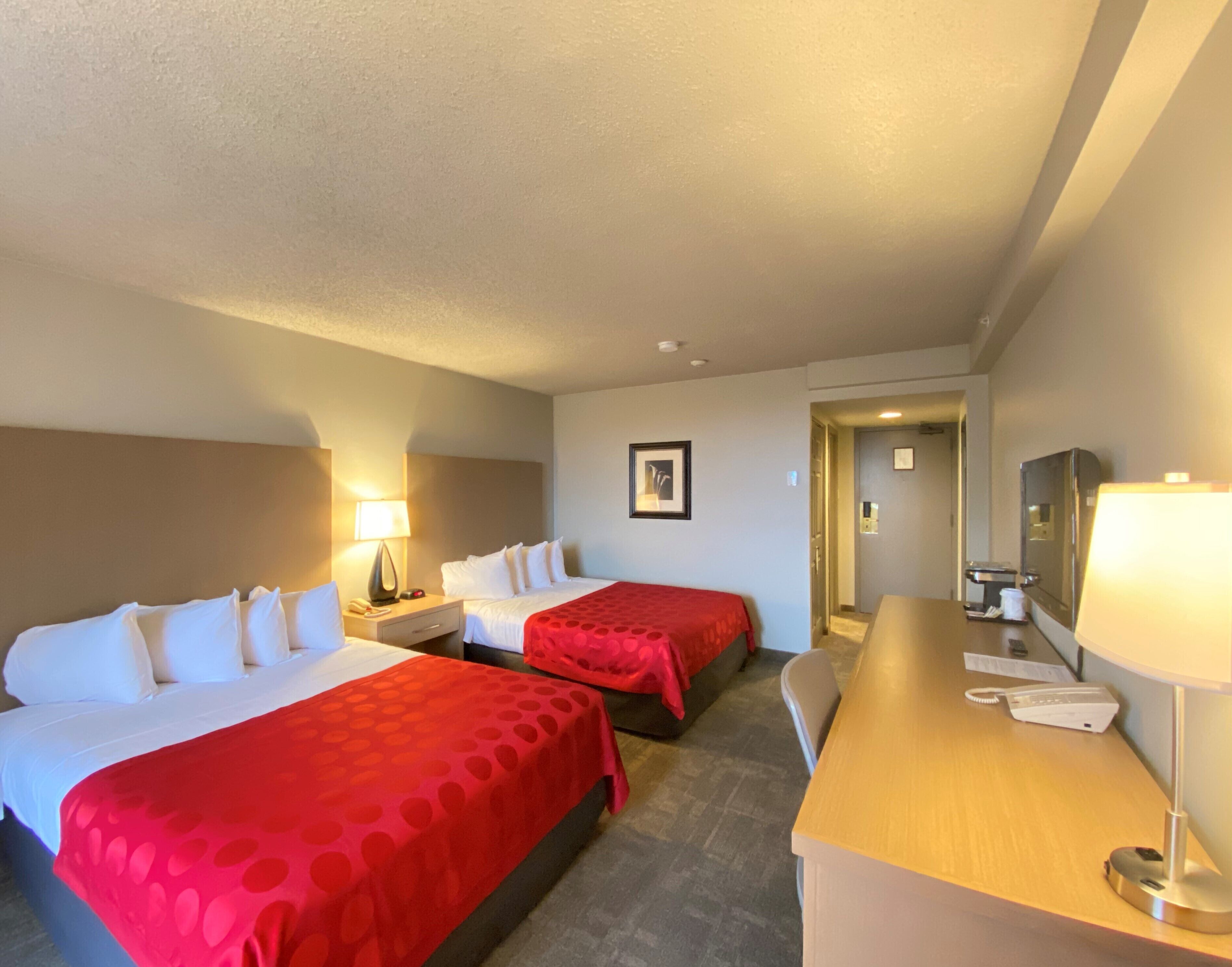 Une chambre d’hôtel avec deux lits, un bureau et une chaise.
