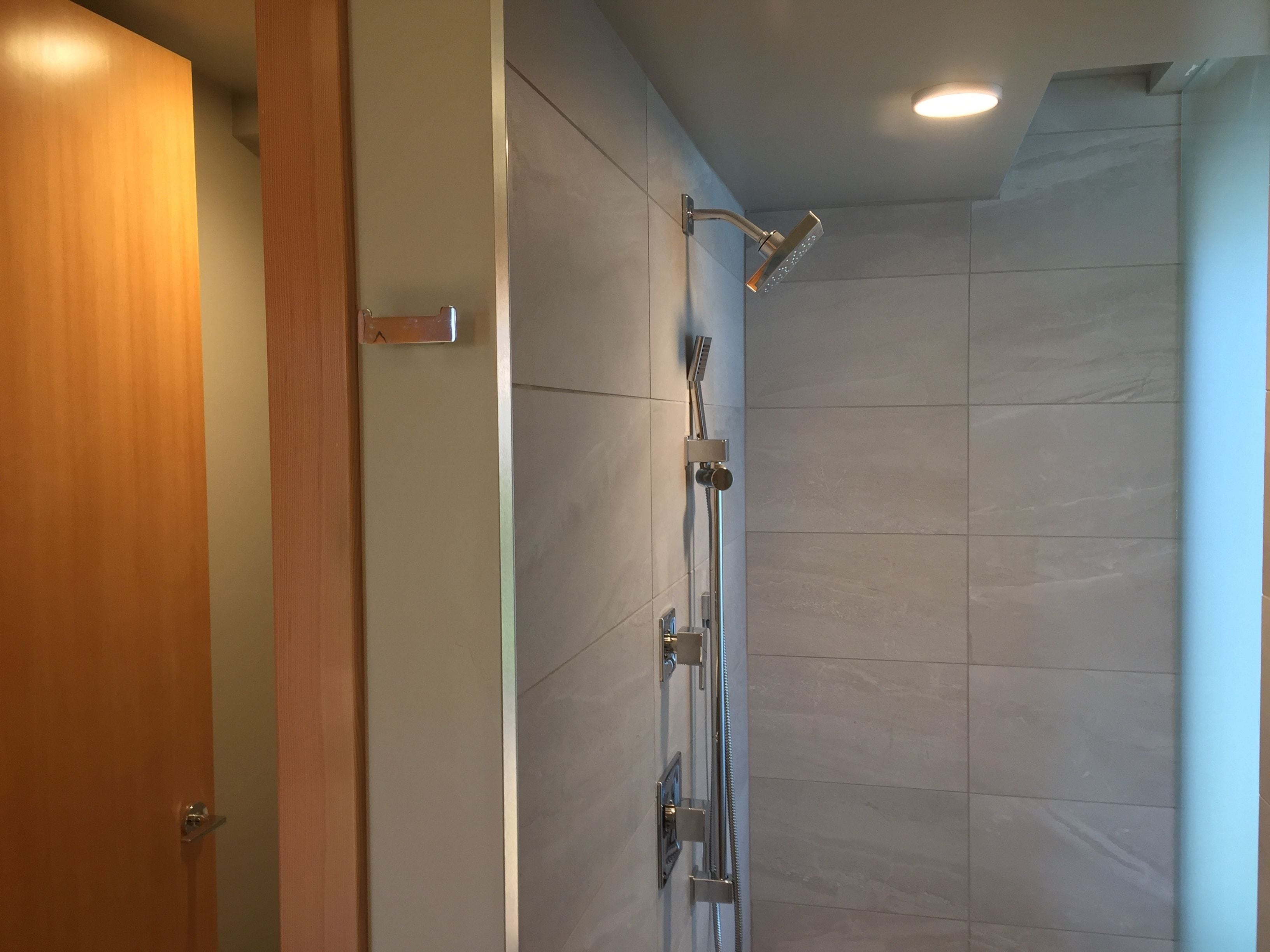 Un baño moderno con ducha, paredes de azulejos y una puerta de madera.