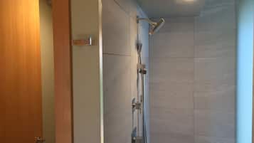 Un baño moderno con ducha, paredes de azulejos y una puerta de madera.