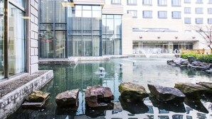 A modern building with large windows and a water feature with rocks.