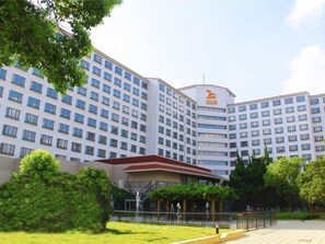 Un hotel de varios pisos con fachada uniforme, numerosos ventanales y una entrada central con tejado rojo.