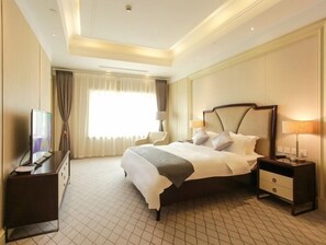 Una habitación de hotel con una cama grande, mesitas de noche, un escritorio y un televisor.
