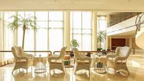 A spacious lobby with a high ceiling, large windows, and a polished marble floor.