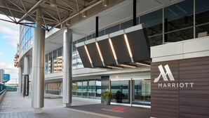 A modern hotel entrance with a large sign for Marriott, a Starbucks Coffee shop, and a pedestrian walkway.