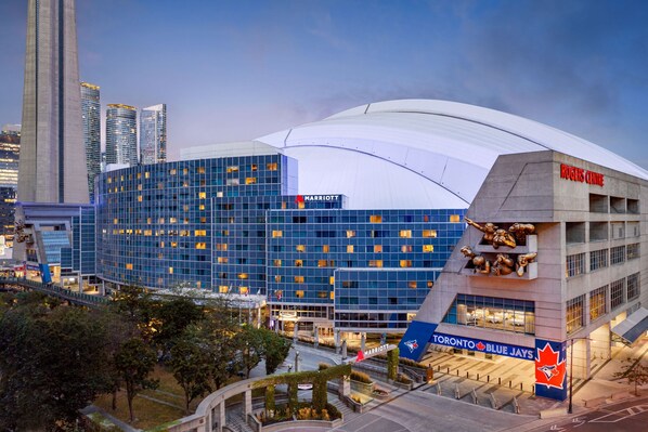 Un hotel moderno con un techo curvo destacado, el logotipo de Marriott y el logotipo de los Blue Jays de Toronto.