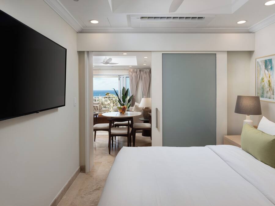 Una habitación de hotel con cama, televisor, escritorio y silla, y vista al océano.