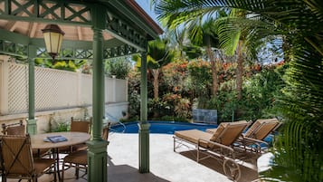 Un patio techado con piscina, sillones de descanso y una mesa con sillas.