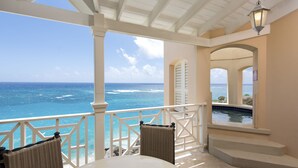 Un espace extérieur abrité avec vue sur l’océan, une piscine et une table avec des chaises.