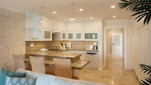 A modern kitchen with granite countertops, white cabinetry, and a built-in dishwasher.