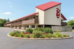 Un hotel Red Roof Inn con techo rojo, fachada color beige y estacionamiento.