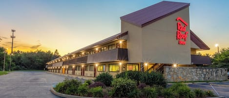 A Red Roof Inn with a two-story structure, a stone facade, and a parking lot.