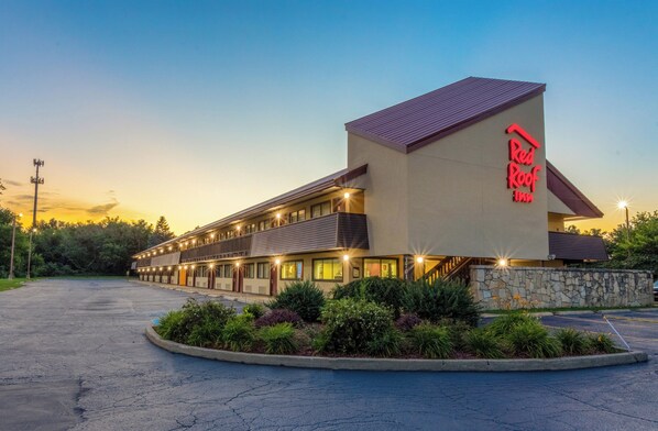 Un Red Roof Inn con una estructura de dos pisos, fachada de piedra y un estacionamiento.