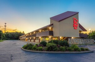 Un Red Roof Inn con una estructura de dos pisos, fachada de piedra y un estacionamiento.