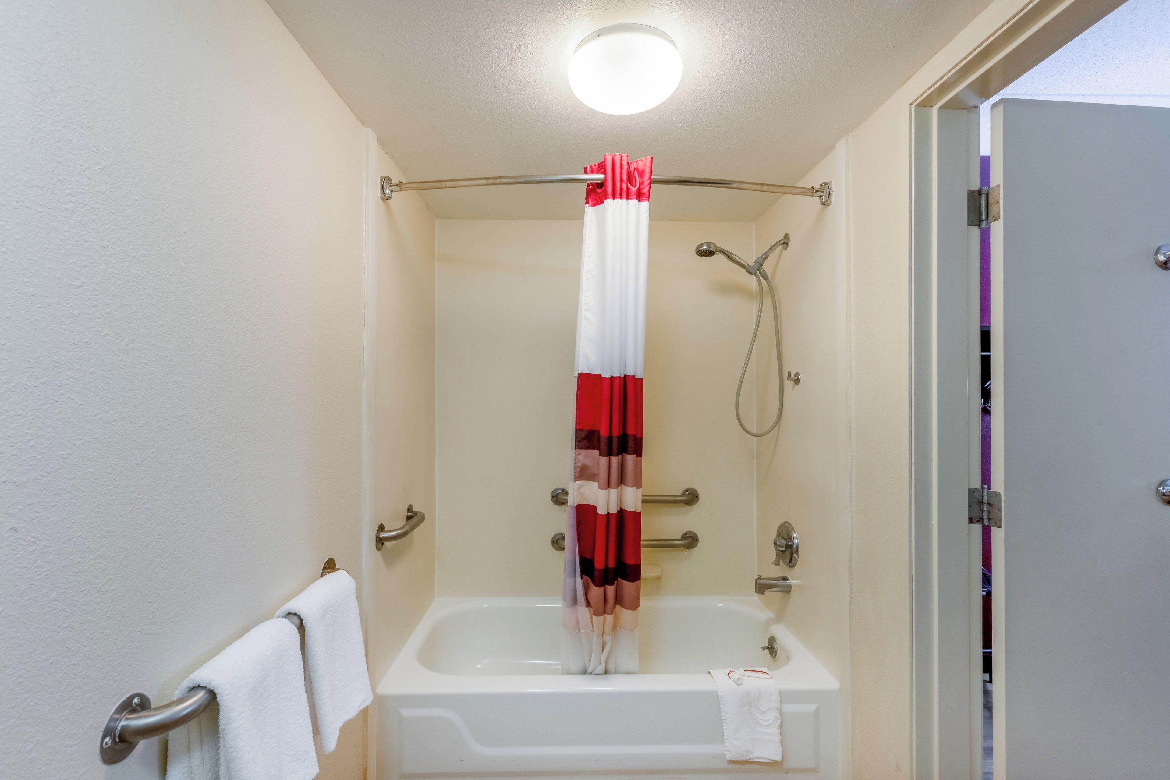 A bathroom with a bathtub, a shower, and a door with a towel rack.