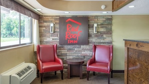 A Red Roof Inn reception area with two leather chairs, a stone wall, and a small round table. - Red Roof Inn Kalamazoo East - Expo Center (Kalamazoo)