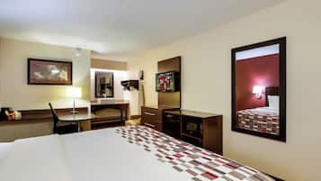A hotel room with a bed, desk, chair, and a large mirror.