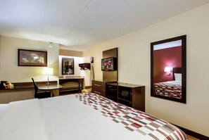 A hotel room with a bed, desk, chair, and a large mirror. - Red Roof Inn Kalamazoo East - Expo Center (Kalamazoo)